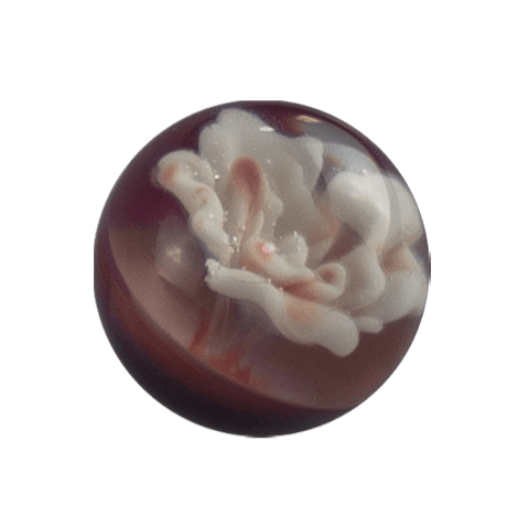 This is an Implosion Flower Marble by Biting Glass available at Handmade Glass Co. A handmade borosilicate glass marble featuring vibrant striking purple rainbow glass. 